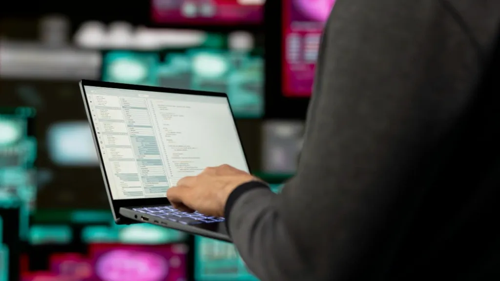 Trabajador informático con un ordenador portátil en un entorno tecnológico.