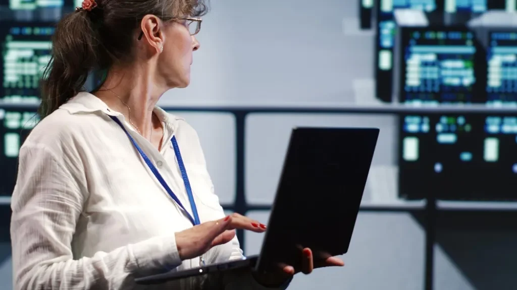Mujer informática trabajando en un entorno de servidores con su laptop.