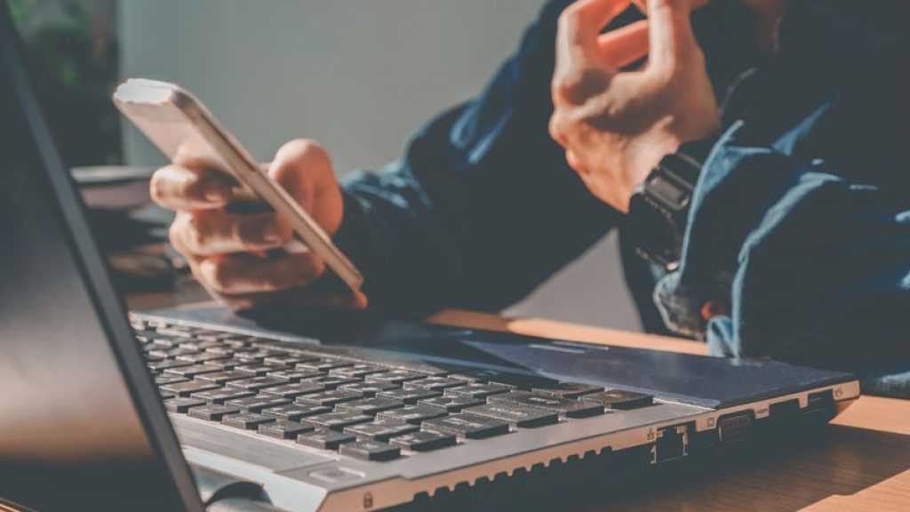 Man's using laptop with blank screen on desk in home interior. B