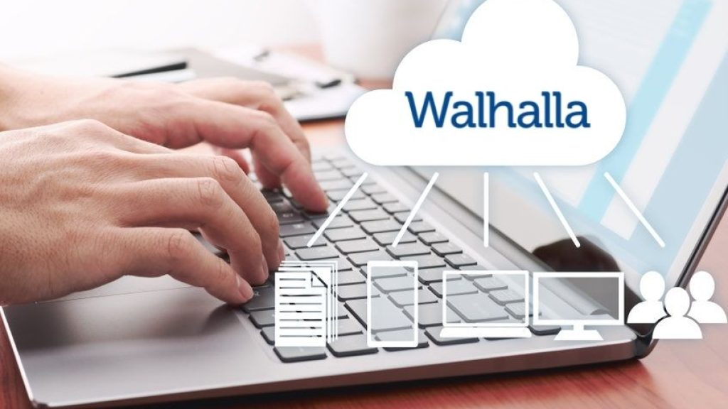 una persona tecleando en un ordenador portátil. vemos superpuesto el logo de Walhalla dentro de una infografía que muestra una nube conectada a varios dispositivos